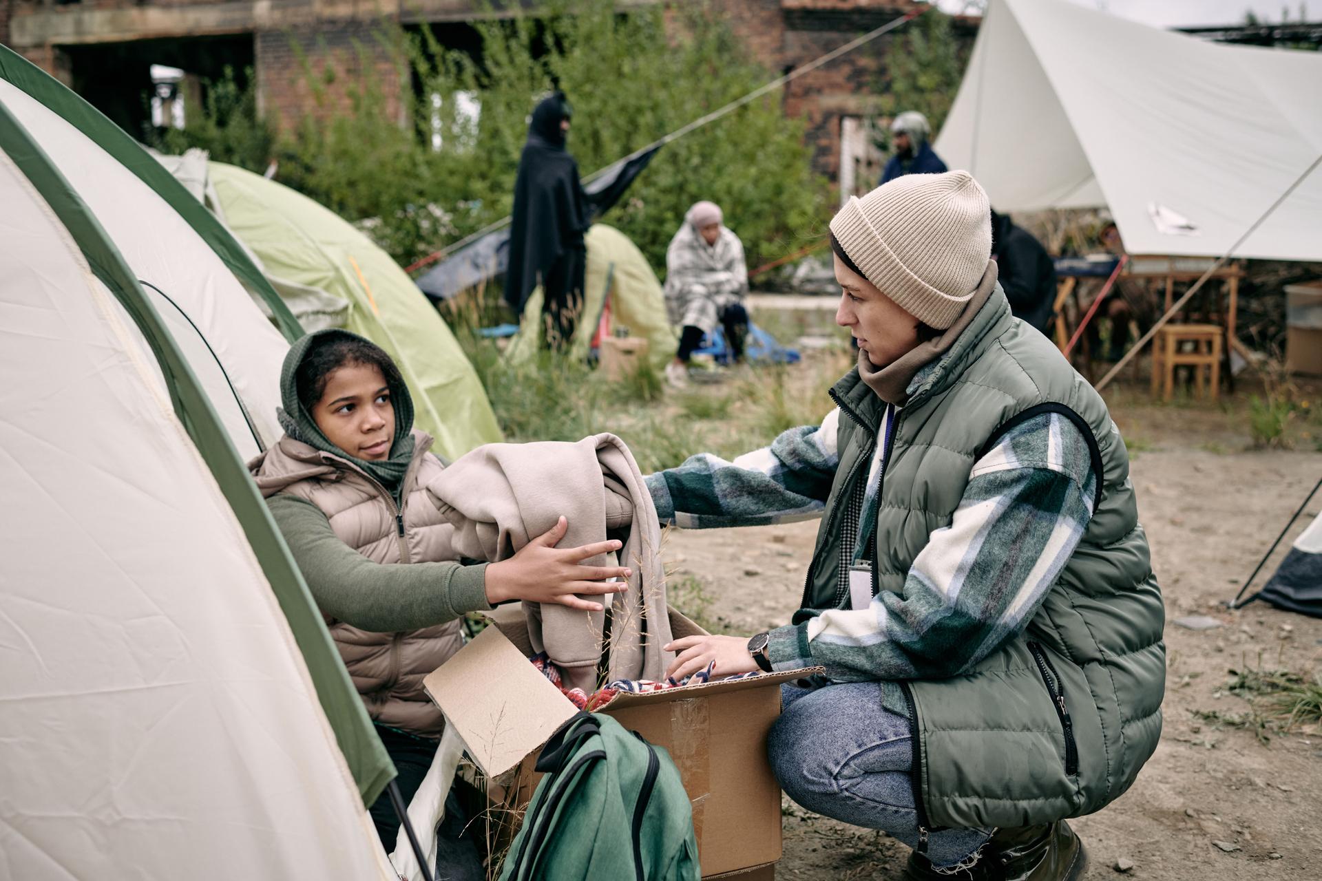 Young female volunteer passing clothes to child