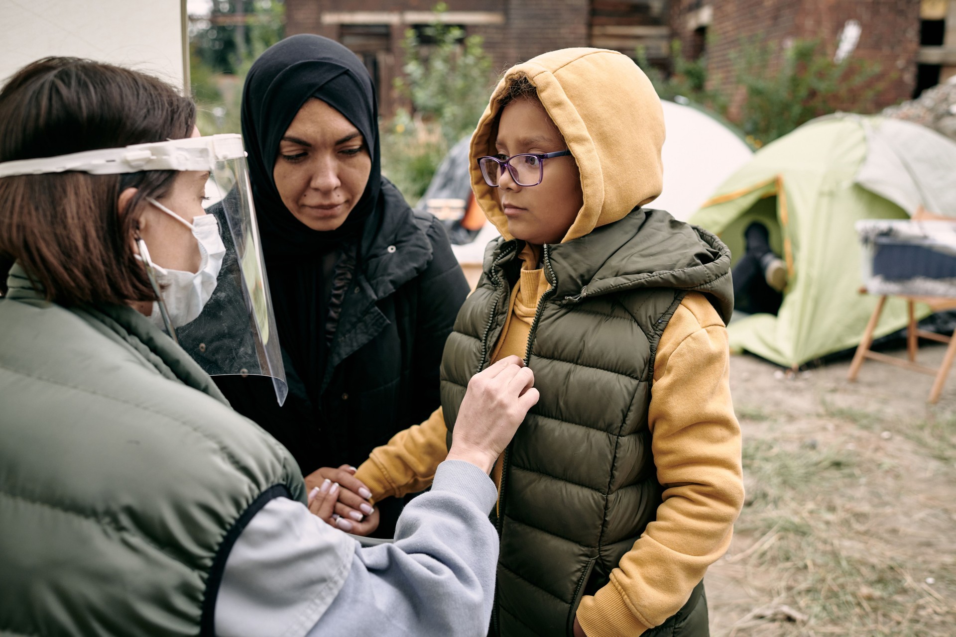 Young volunteer in protective mask and screen examining little girl